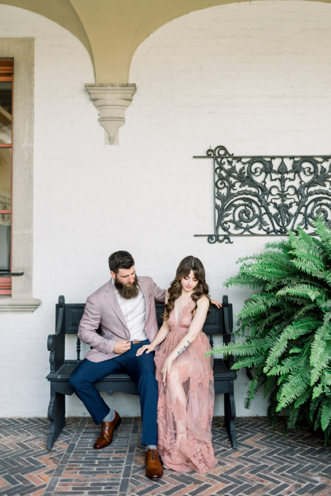 bride and groom sitting on bench at their engagement session