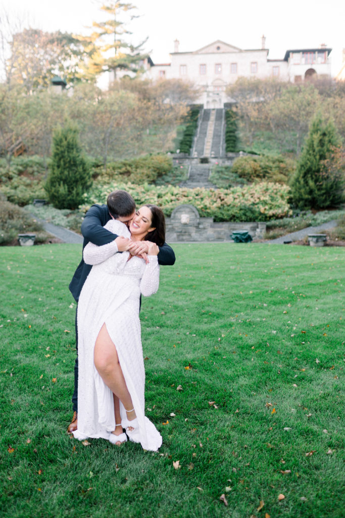 groom kissing bride in garden with a villa in the background