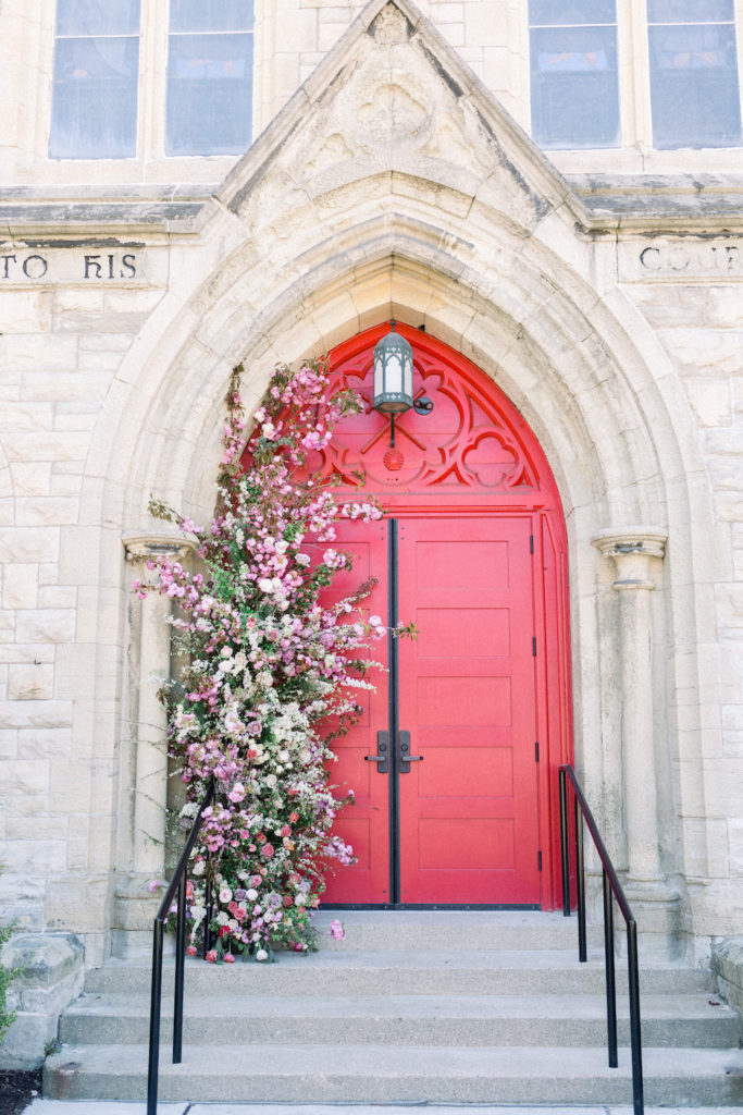 red doors to church with flower arch