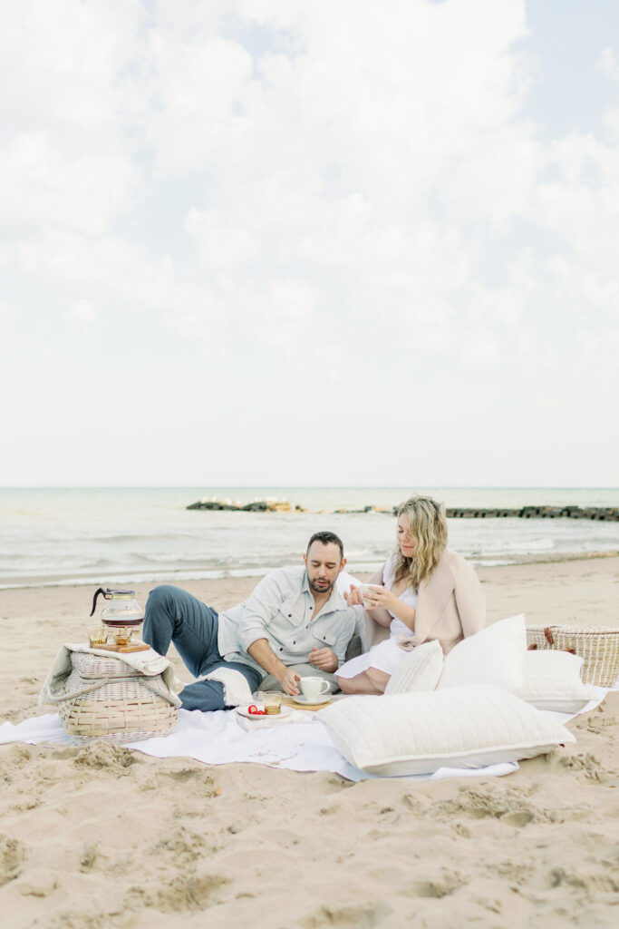 couple laying on beach and drinking coffee
