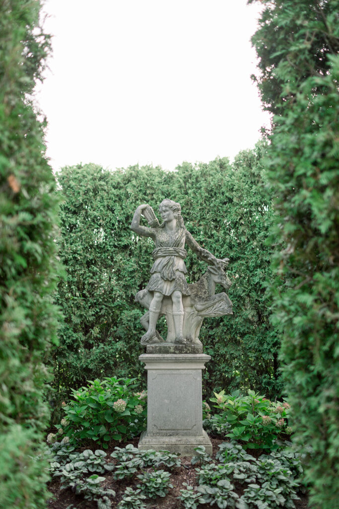 stone statue by dense green bushes