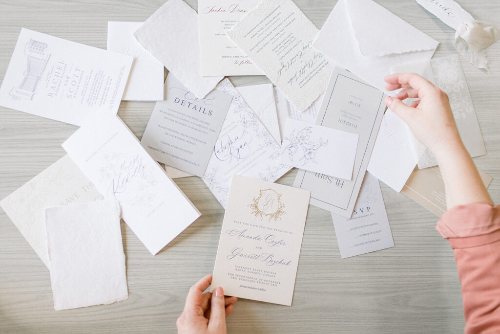 wedding invitations all over table with hands holding one
